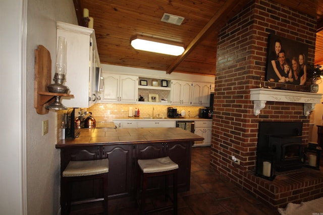 kitchen featuring lofted ceiling, a kitchen breakfast bar, white cabinets, wooden ceiling, and tasteful backsplash