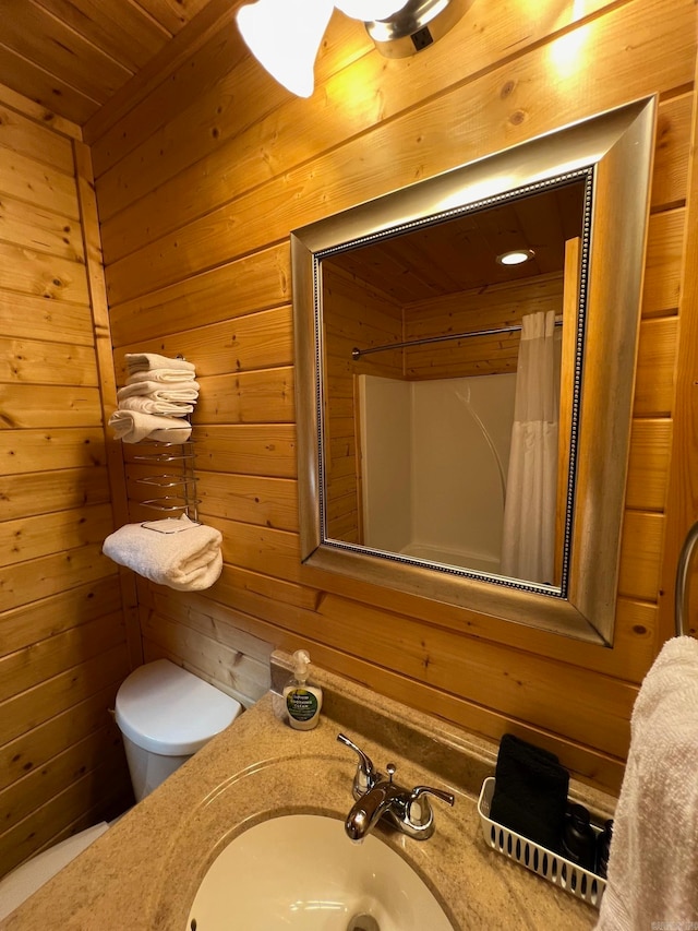 bathroom featuring a shower with shower curtain, toilet, sink, and wood walls