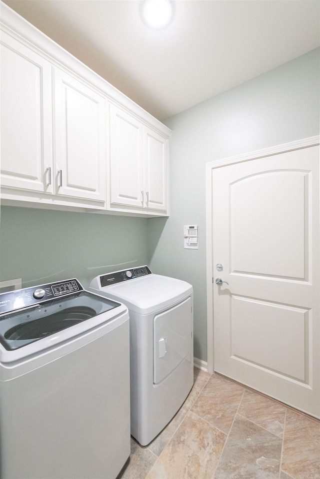 washroom featuring cabinets, light tile floors, and washing machine and dryer