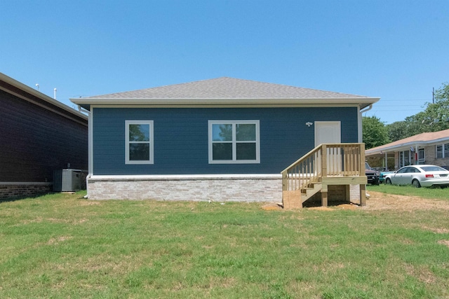 back of house featuring a lawn and central air condition unit