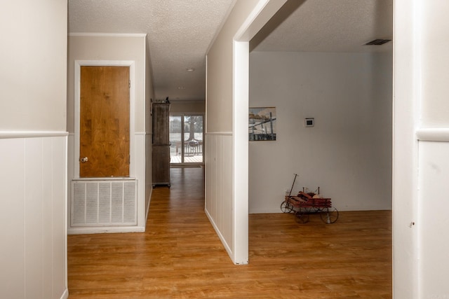 hall featuring light hardwood / wood-style floors and a textured ceiling