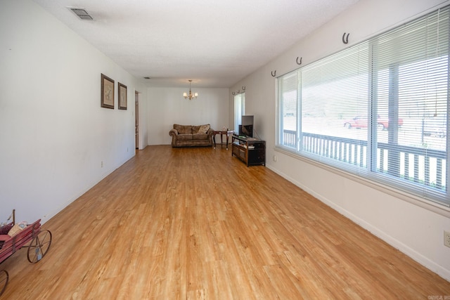 unfurnished living room featuring light hardwood / wood-style flooring and a chandelier