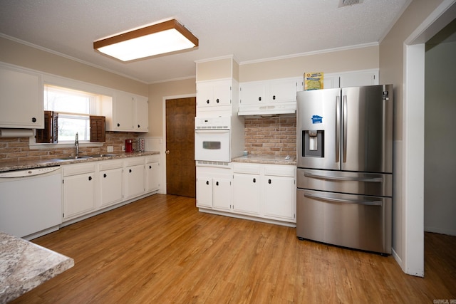 kitchen featuring white cabinets, backsplash, light hardwood / wood-style floors, and white appliances