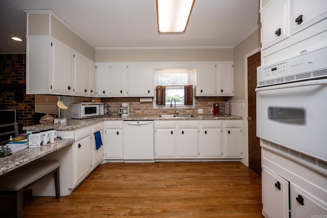 kitchen with sink, light wood-type flooring, white cabinets, and dishwasher