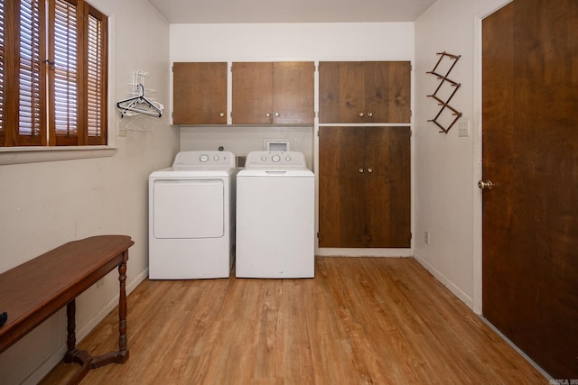 laundry area with cabinets, separate washer and dryer, and light hardwood / wood-style floors