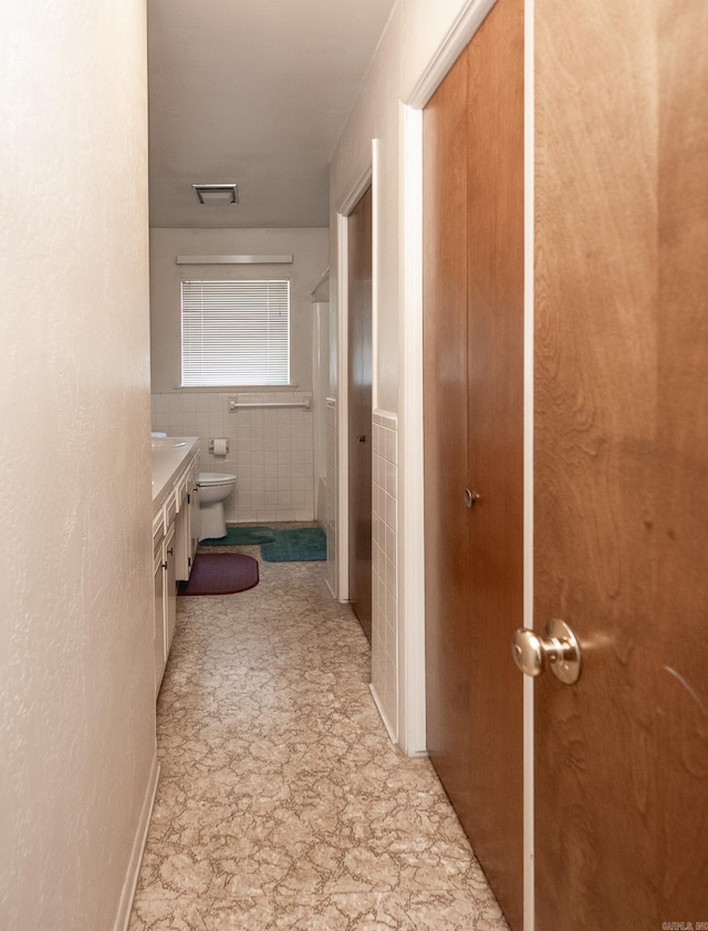 corridor with light tile floors and tile walls