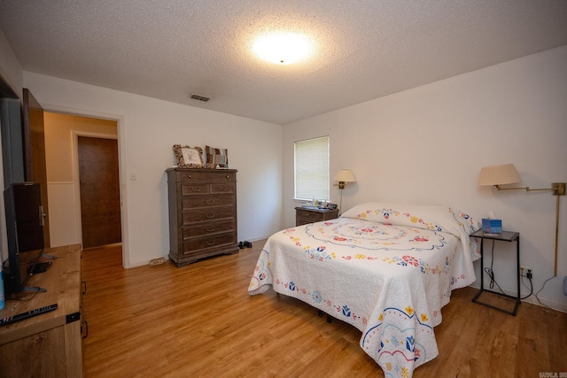 bedroom featuring light hardwood / wood-style flooring and a textured ceiling