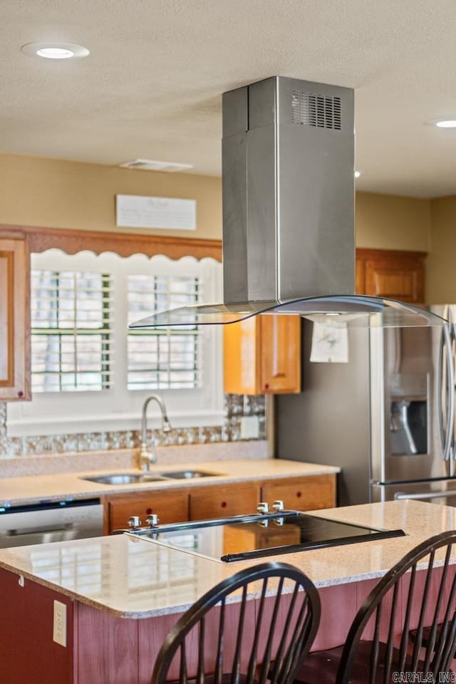 kitchen with sink, island exhaust hood, light stone counters, a breakfast bar, and a center island