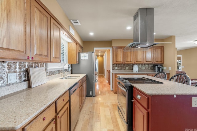 kitchen featuring backsplash, light hardwood / wood-style floors, sink, stainless steel appliances, and island range hood