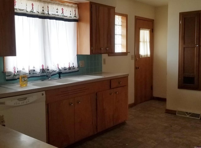 kitchen with white dishwasher, dark tile flooring, backsplash, and sink