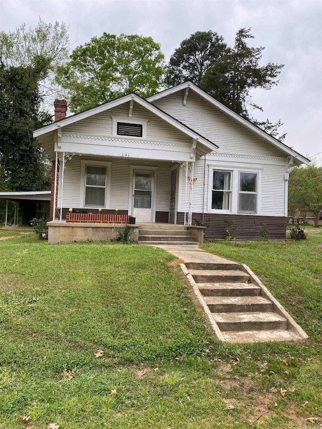 bungalow with covered porch and a front yard