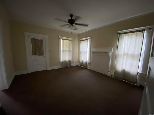 unfurnished bedroom with dark colored carpet, ceiling fan, and multiple windows