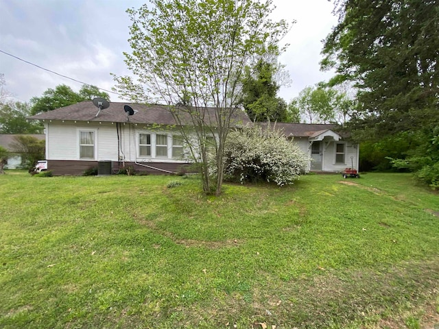 rear view of property with central AC unit and a lawn