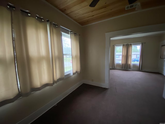 empty room with ceiling fan, crown molding, dark colored carpet, and wooden ceiling