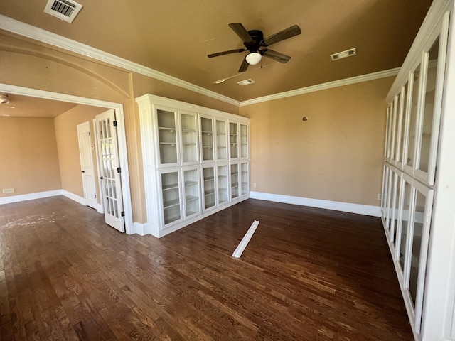 empty room featuring dark wood-type flooring, ceiling fan, french doors, and crown molding