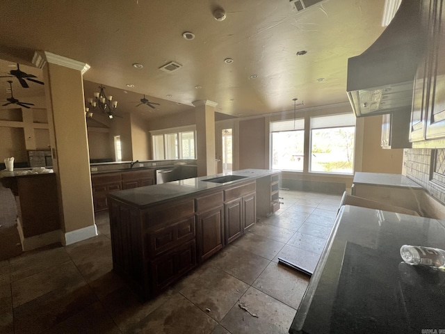 kitchen featuring dark brown cabinetry, ceiling fan, dark tile flooring, wall chimney range hood, and decorative columns