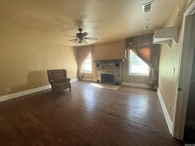 unfurnished room with ceiling fan, dark hardwood / wood-style floors, and a stone fireplace