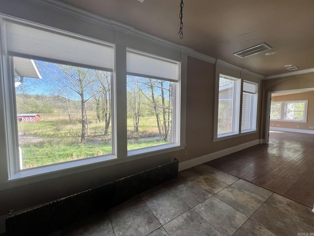 empty room featuring plenty of natural light, dark tile flooring, and ornamental molding