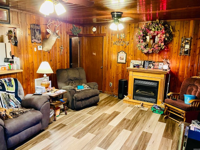 living room with ceiling fan, light hardwood / wood-style floors, wooden walls, and wooden ceiling