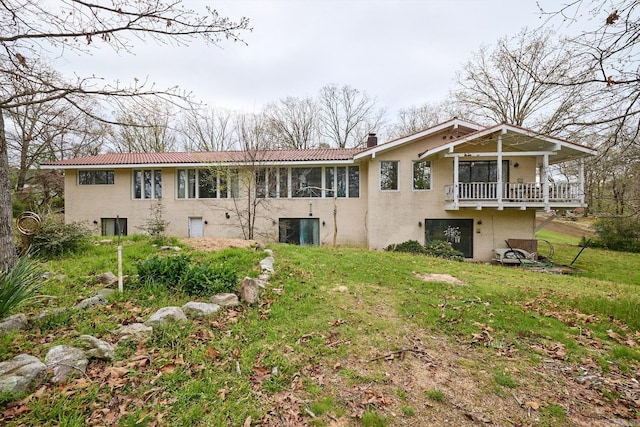 rear view of house featuring a balcony and a lawn