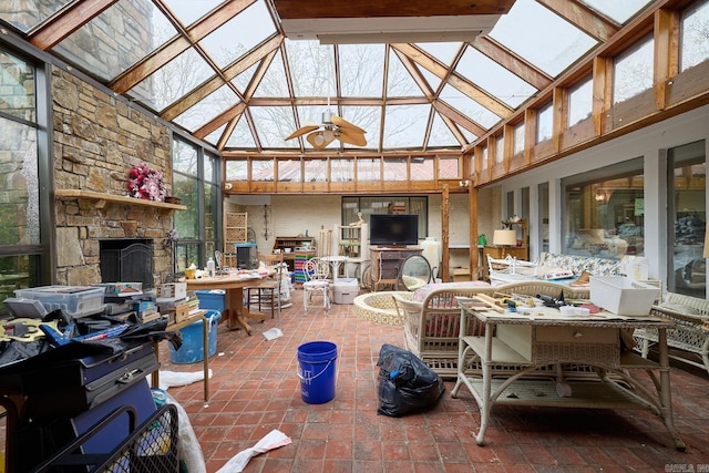 sunroom / solarium with vaulted ceiling with skylight, a fireplace, and ceiling fan