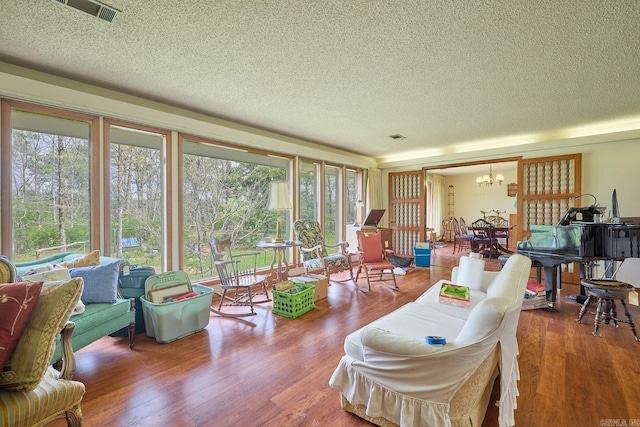 living room with hardwood / wood-style floors, a textured ceiling, and a notable chandelier