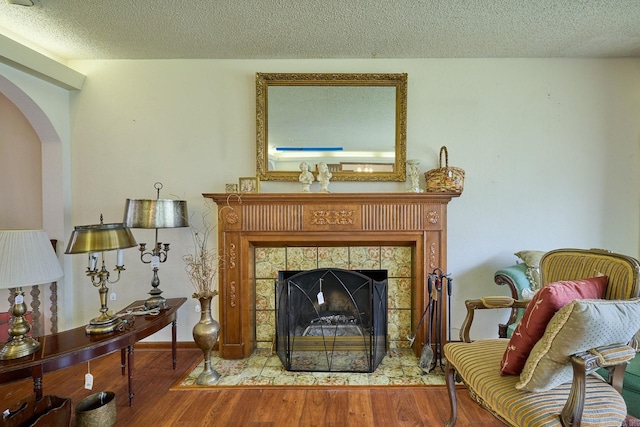 sitting room with a fireplace, wood-type flooring, and a textured ceiling