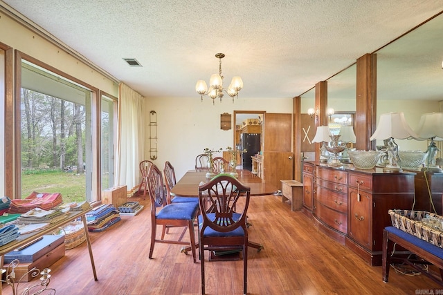 dining area featuring a chandelier, hardwood / wood-style floors, and a textured ceiling