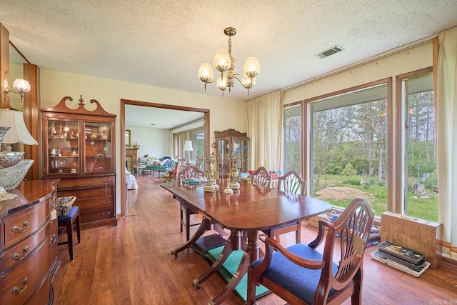 dining area with hardwood / wood-style flooring, a textured ceiling, and an inviting chandelier