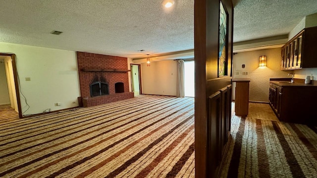 carpeted living room with a brick fireplace, sink, and a textured ceiling