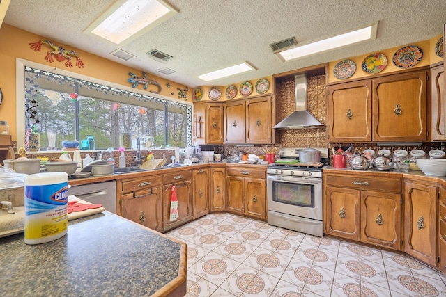 kitchen with sink, a textured ceiling, stainless steel appliances, and wall chimney exhaust hood