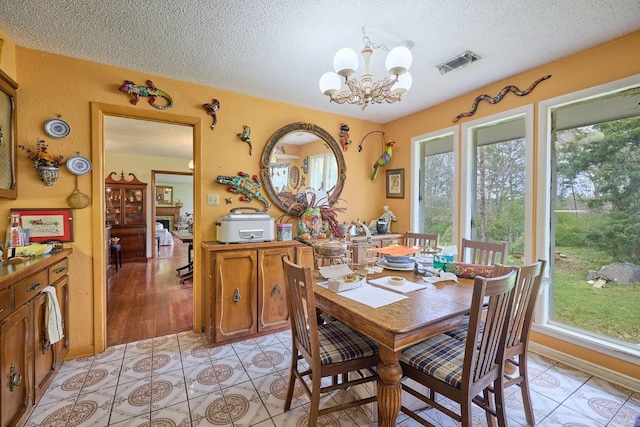 dining room featuring light tile patterned flooring, a notable chandelier, and a textured ceiling