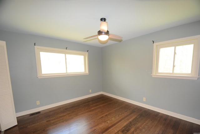 unfurnished room with a healthy amount of sunlight, ceiling fan, and dark wood-type flooring