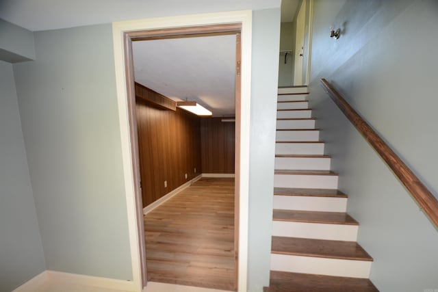 stairs with wooden walls and light hardwood / wood-style floors