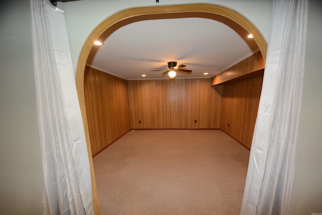 unfurnished room featuring light colored carpet, wood walls, ornamental molding, and ceiling fan