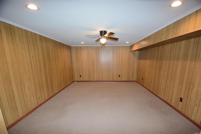 unfurnished room with wood walls, light carpet, crown molding, and ceiling fan