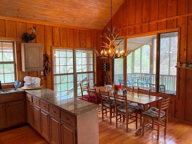 kitchen featuring light hardwood / wood-style flooring, vaulted ceiling, and wooden walls