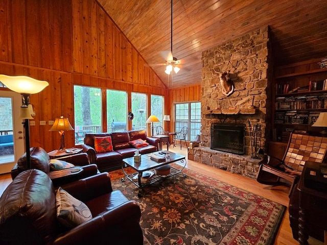 living room featuring a stone fireplace, high vaulted ceiling, hardwood / wood-style floors, wooden ceiling, and wood walls