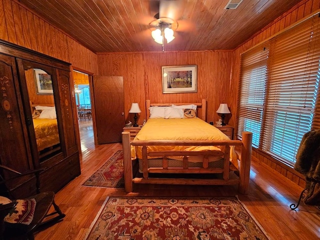 bedroom with wooden walls, wood-type flooring, wooden ceiling, and multiple windows