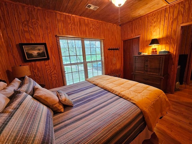 bedroom with hardwood / wood-style floors, wooden ceiling, and wooden walls