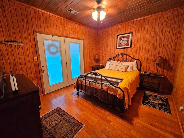 bedroom with wooden ceiling, wood-type flooring, ceiling fan, and wooden walls