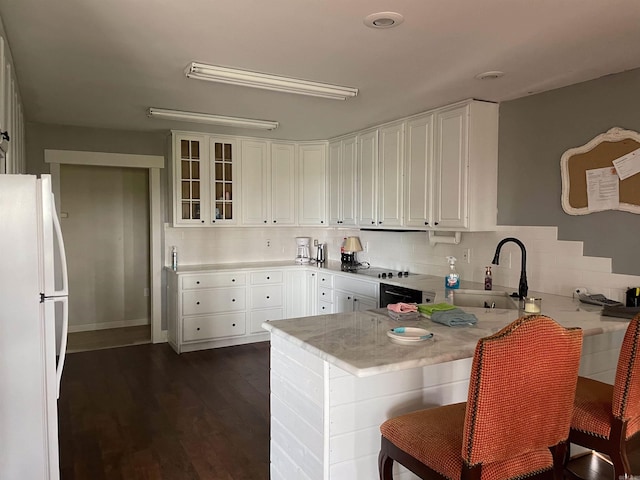 kitchen with a kitchen breakfast bar, sink, dark hardwood / wood-style flooring, white refrigerator, and white cabinetry