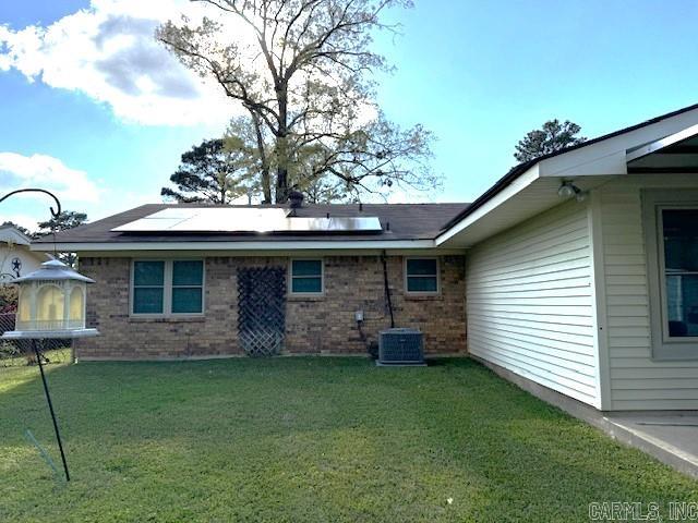 rear view of property featuring central air condition unit and a yard