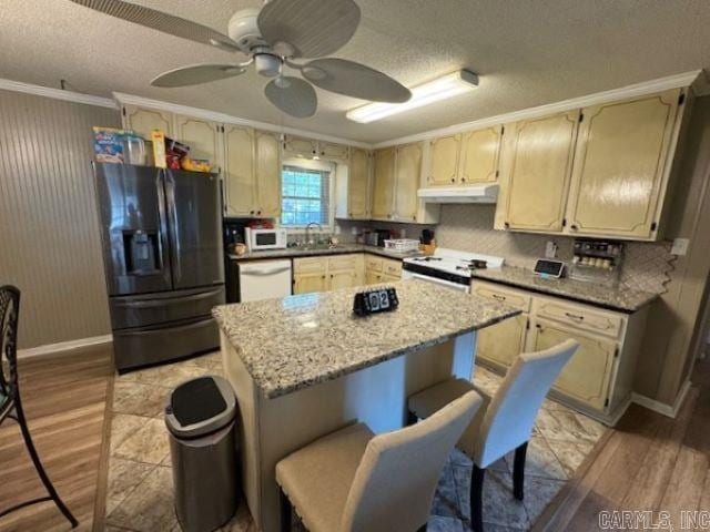 kitchen with backsplash, ceiling fan, white appliances, light hardwood / wood-style floors, and crown molding