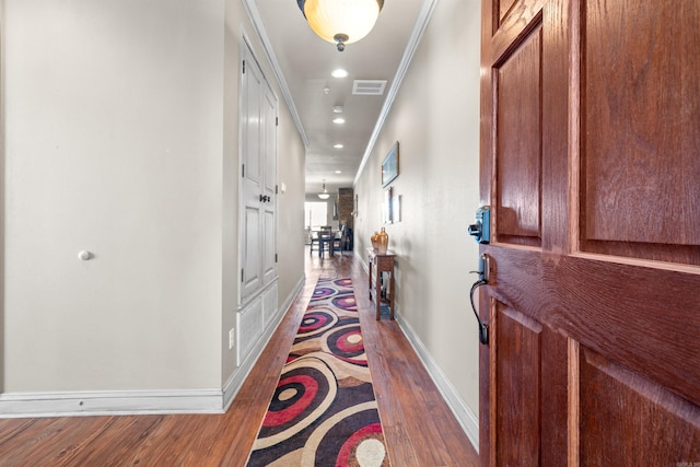 corridor with ornamental molding and light hardwood / wood-style flooring