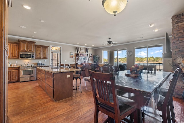 dining space with ceiling fan, crown molding, brick wall, and hardwood / wood-style floors