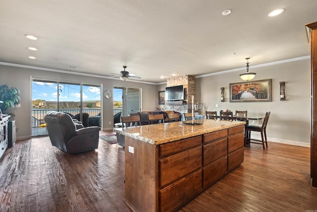 kitchen with dark wood-type flooring, a center island, light stone counters, ceiling fan, and brick wall