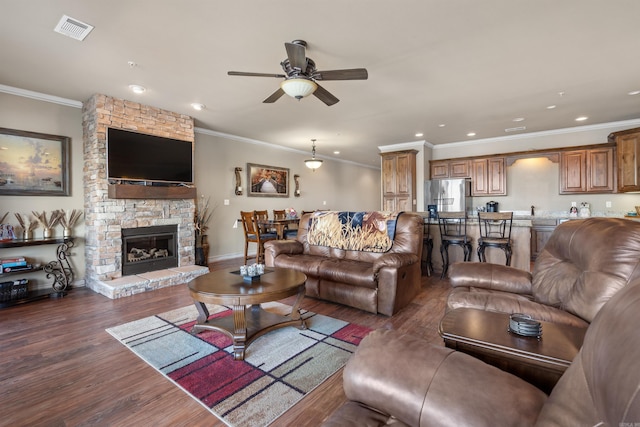 living room with ornamental molding, ceiling fan, dark hardwood / wood-style flooring, and a fireplace