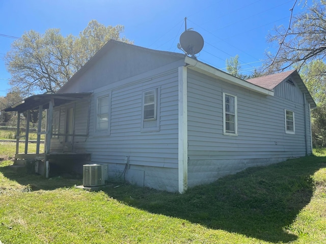 view of side of property with central AC unit and a lawn