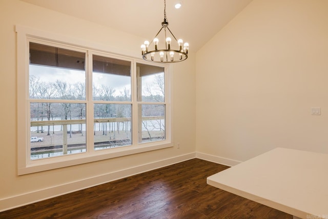 unfurnished dining area with dark hardwood / wood-style flooring, vaulted ceiling, and an inviting chandelier